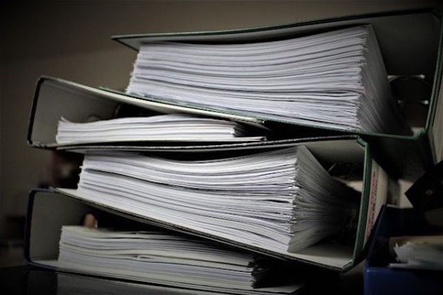 Piles of paperwork from working forensic accounting criminal cases feature