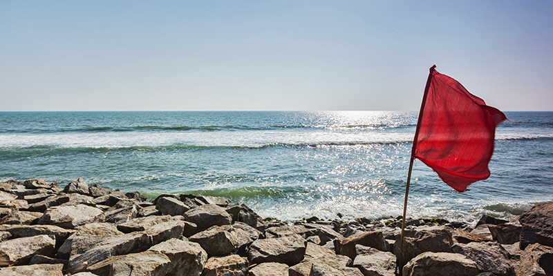 red-flag-on-rocky-beach