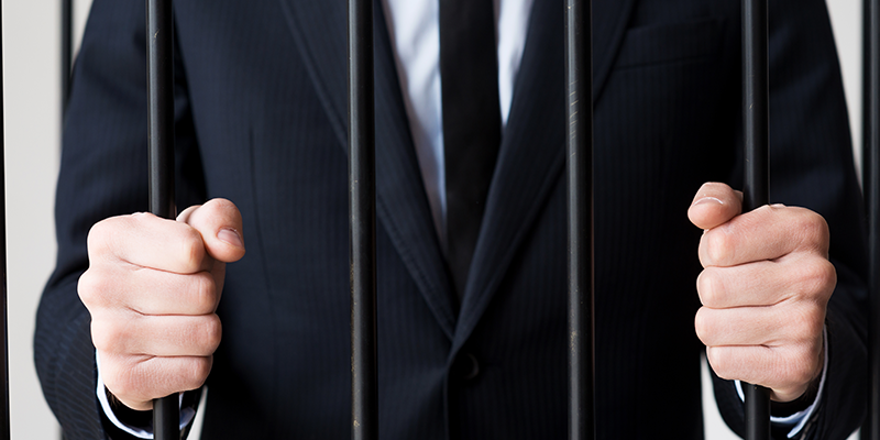 businessman-in-suit-behind-bars-prison
